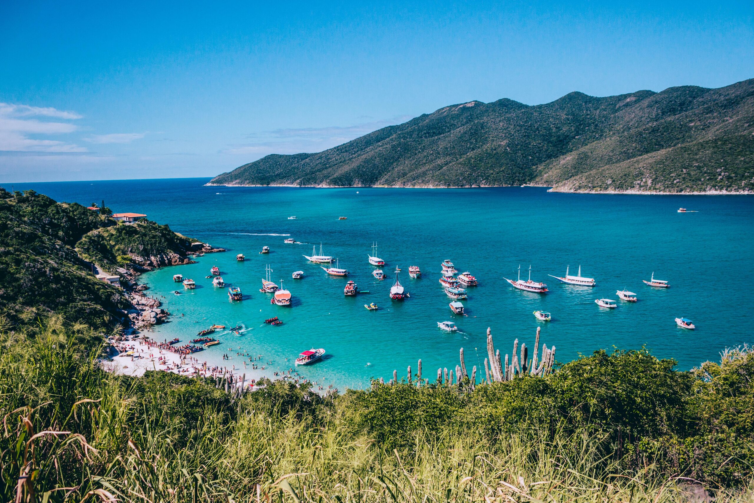 Explore the vibrant turquoise waters and boats at Arraial do Cabo's beautiful coast in summer.