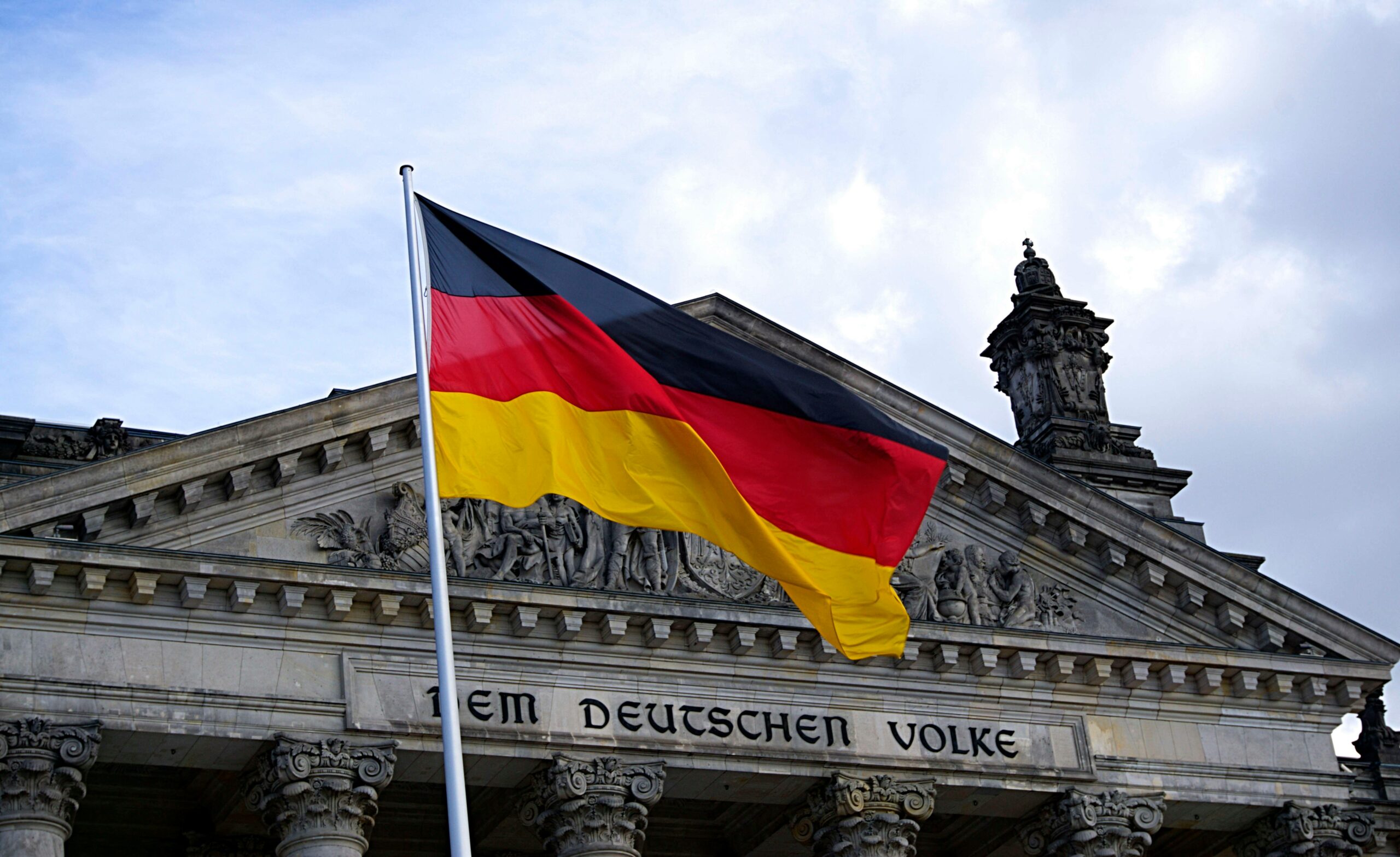 German national flag waving in front of the Reichstag building in Berlin, a symbol of democracy.