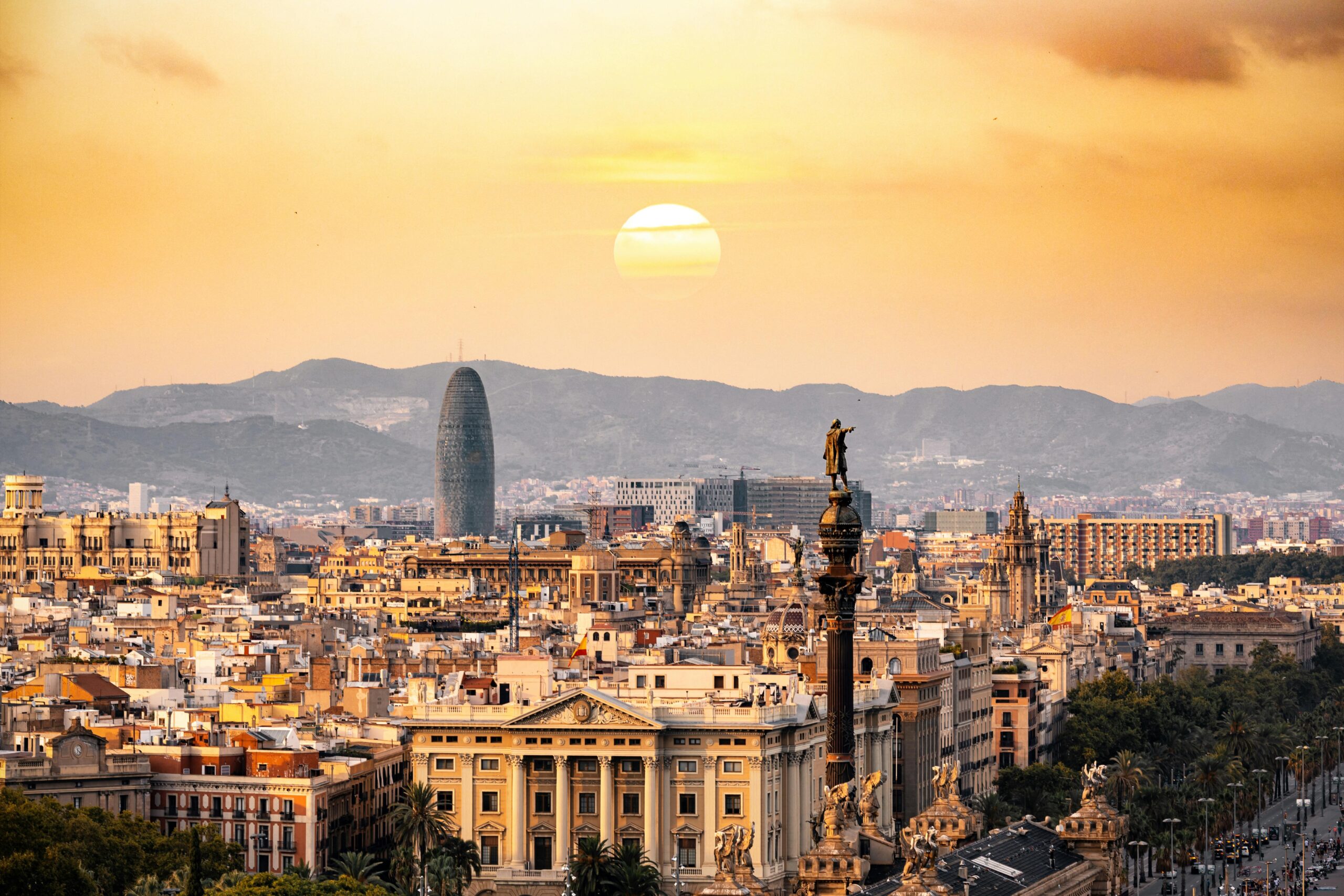 A stunning sunset view of the Barcelona skyline showcasing iconic landmarks and a warm, golden hour glow.