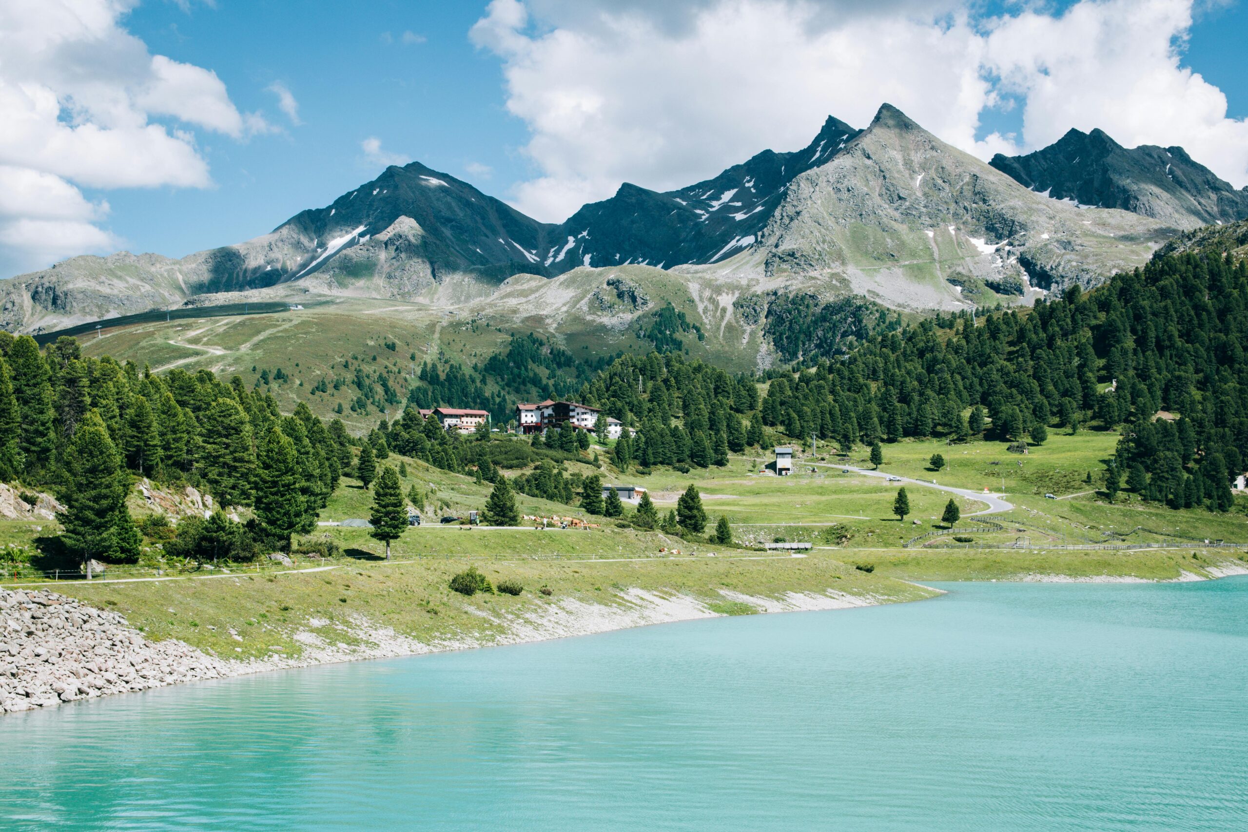 Scenic view of the Austrian Alps with a turquoise lake and lush greenery under a clear blue sky.