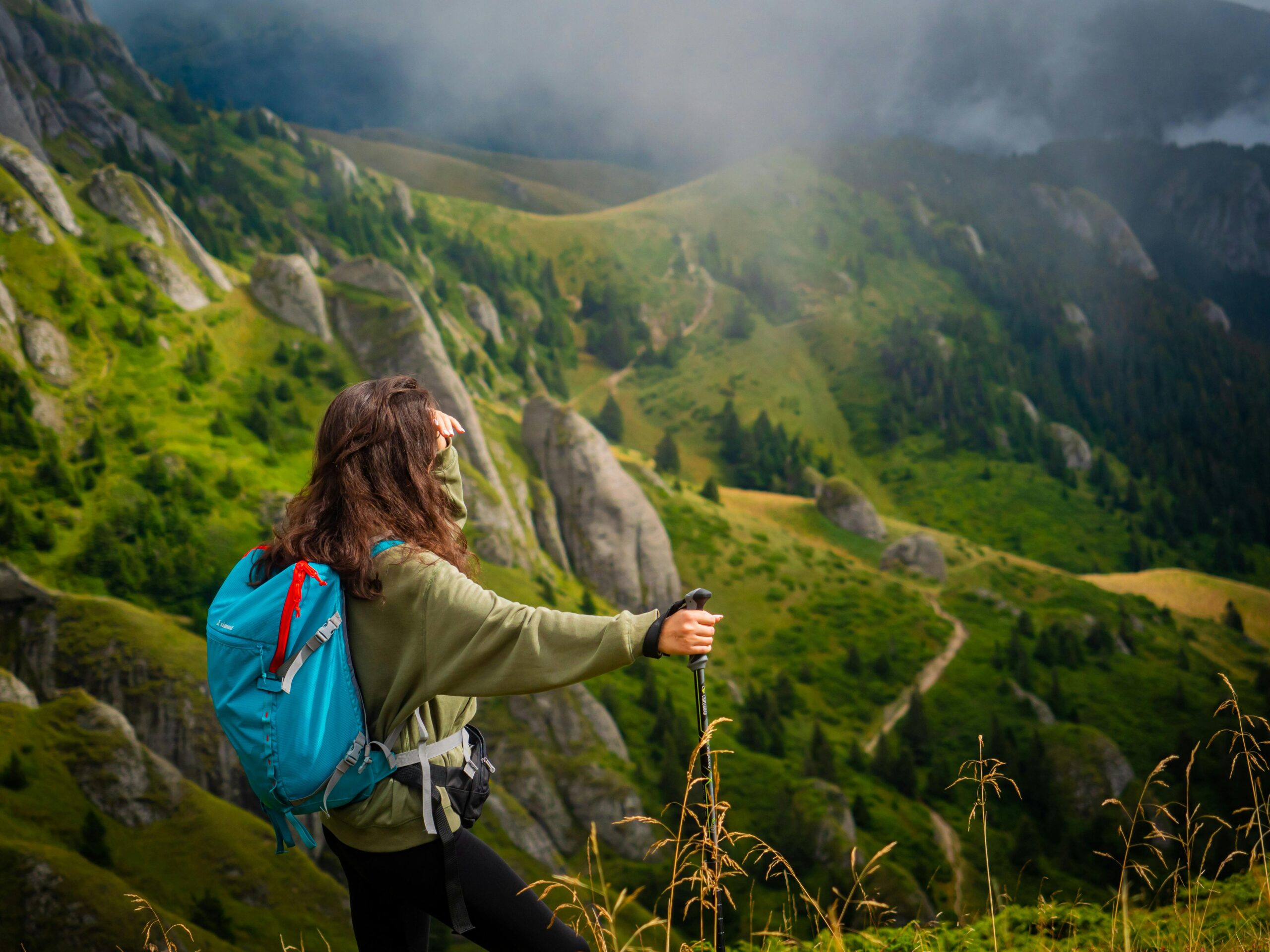 A woman hiker enjoys a breathtaking mountain view in Romania, perfect for adventure and travel photography.