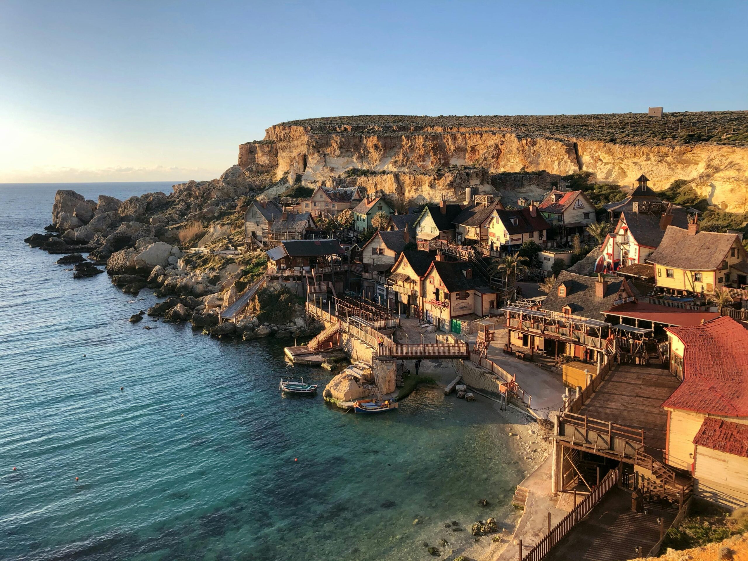 Picturesque cliffside view of Popeye Village in Il-Mellieħa, Malta with clear blue waters.