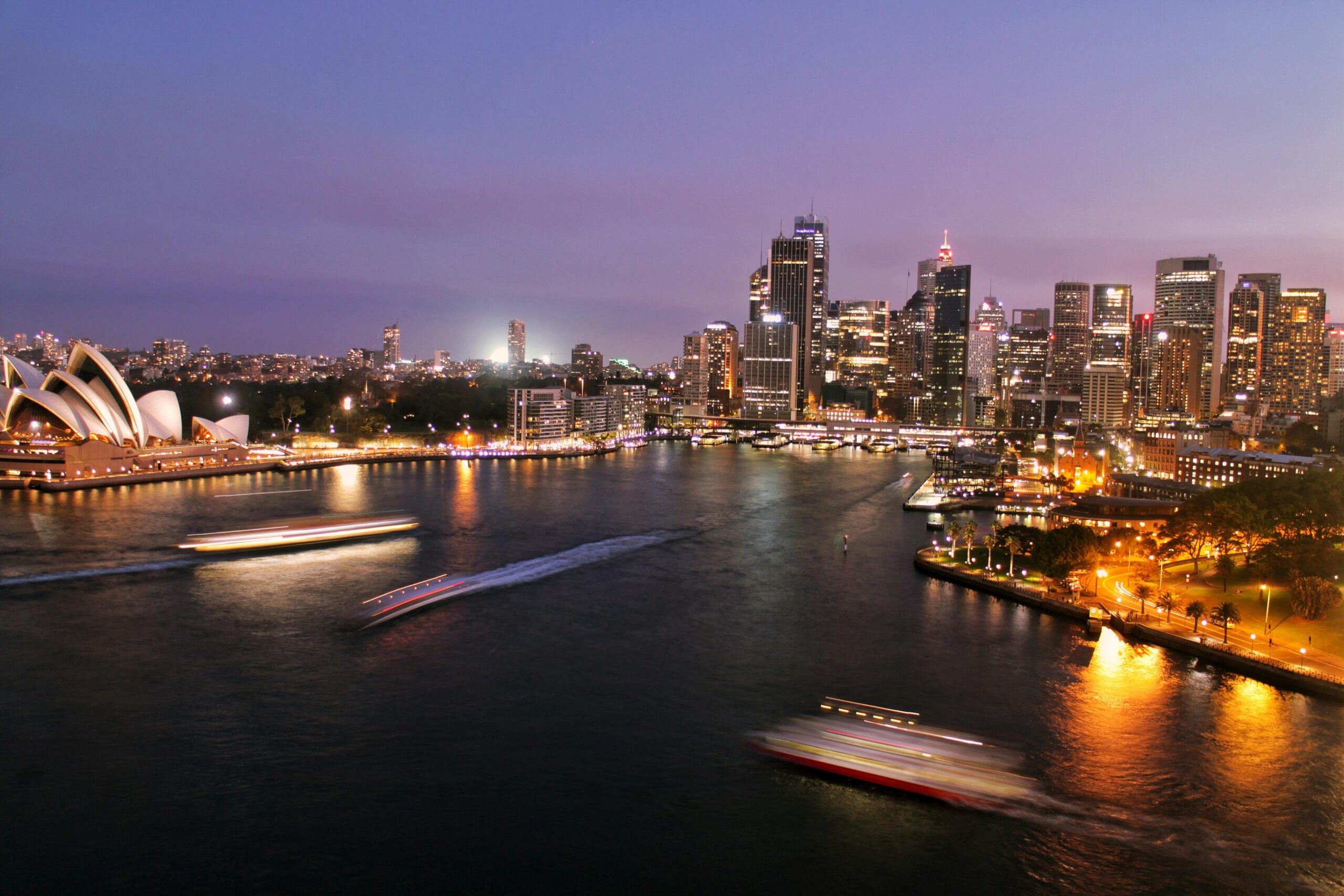 Captivating view of Sydney's illuminated skyline with the iconic Opera House and harbor at night.