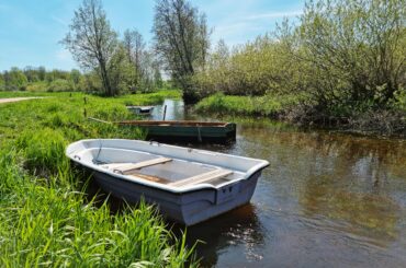 Peaceful riverbank in Õisu, Estonia with docked boats and lush greenery.