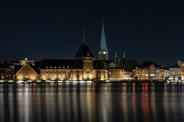 Scenic night view of Aarhus waterfront with illuminated historic buildings reflecting in the water.