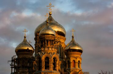 Stunning view of St. Nicholas Naval Cathedral's golden domes glowing at sunset in Latvia.