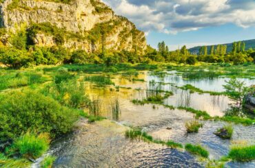 Lush landscape with rocks, trees, and water at Krka National Park, Croatia.