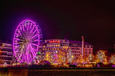 A vibrant Ferris wheel and festive lights illuminate the streets of Luxembourg City at night.