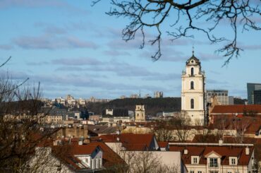 A beautiful view of Vilnius city featuring historic architecture and a prominent church tower under a clear sky.