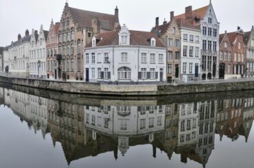 Picturesque canalside view of historic buildings reflecting in Bruges, Belgium.