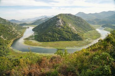Breathtaking aerial view of Rijeka Crnojevića river bend in Montenegro with lush mountains.