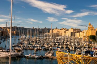 Captivating view of a vibrant marina against Malta's historic skyline under clear blue skies.