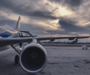 A passenger airplane is parked on the tarmac at sunset, with another aircraft in the background.