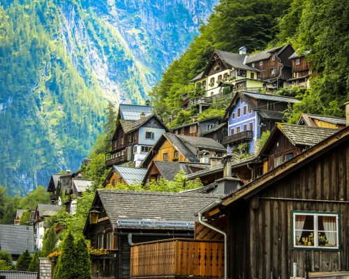 Charming wooden houses on a lush mountainside in Hallstatt, Austria under bright daylight.