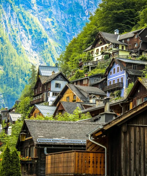Charming wooden houses on a lush mountainside in Hallstatt, Austria under bright daylight.