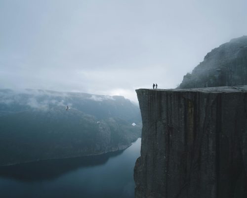 Dramatic view of Preikestolen cliff in Norway with mist and fjord.