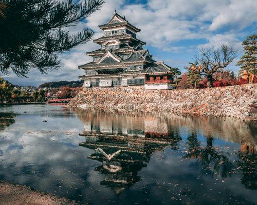 Reflection of Matsumoto Castle in Japan during autumn, surrounded by a serene lake.