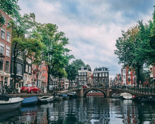 Charming view of an Amsterdam canal lined with bicycles, boats, and historic buildings.