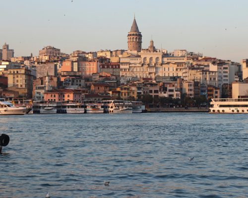 A breathtaking view of the Galata Tower and Istanbul's vibrant waterfront at sunset.