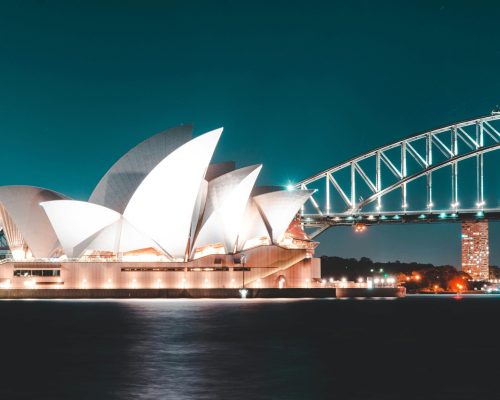 Stunning night view of Sydney Opera House and Harbour Bridge, beautifully illuminated against a clear sky.