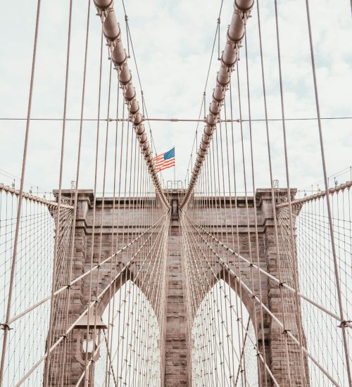 Stunning view of the Brooklyn Bridge with an American flag, symbolizing New York City's architectural grandeur.