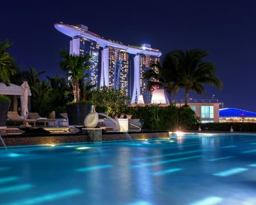 Illuminated Marina Bay Sands hotel above pool at night, capturing Singapore's iconic skyline.