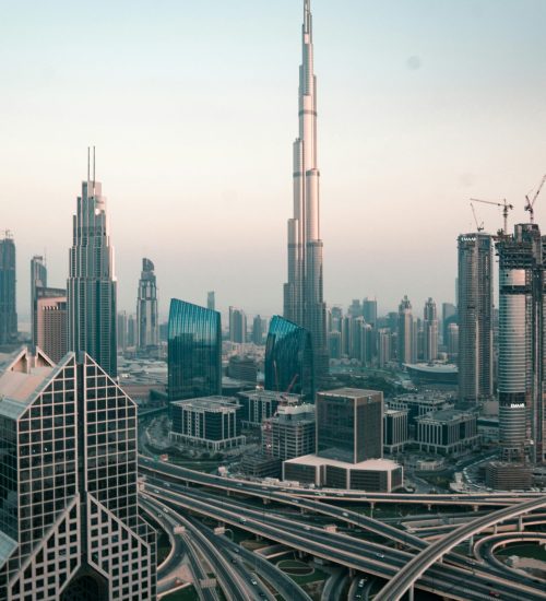 Aerial view of Dubai's skyline with Burj Khalifa and intricate highway system at sunset.