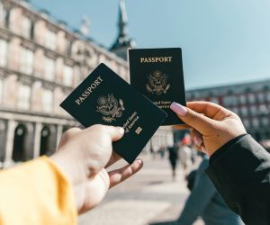 Travelers holding US passports at Plaza Mayor, Madrid, highlighting tourism and exploration.