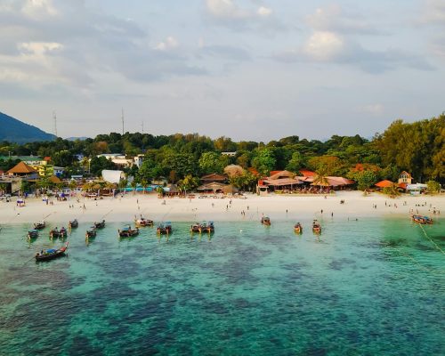 A beautiful aerial view of a tropical beach with boats and lush greenery, ideal for vacation.