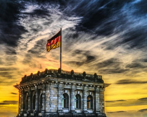 Vibrant sunset over a historic Berlin monument with the German flag waving.
