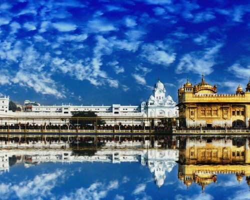 The Golden Temple, Harmandir Sahib, in Amritsar beautifully reflected in water with a vivid blue sky.