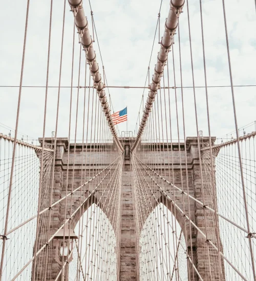 Stunning view of the Brooklyn Bridge with an American flag, symbolizing New York City's architectural grandeur.